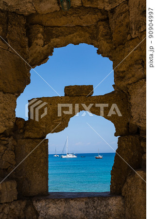 ギリシャ ロードス島のロードスにある城壁の隙間から見えるエーゲ海とボート ギリシャ ロードス島のロードスにある城壁の隙間から見えるエーゲ海とボート 90904997