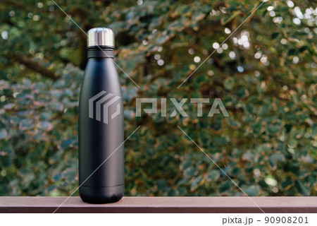 Reusable thermo bottles against green nature summer background. Reusable thermo bottles against green nature summer background. 90908201