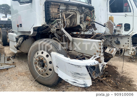 An abandoned truck in a junkyard, a white lorry with a destroyed engine and bumper after a head-on collision on the road, big broken automobile on a car dump 90910006