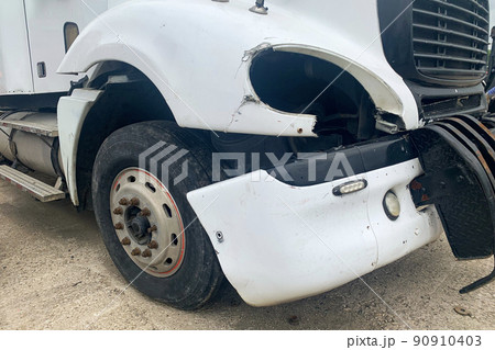 Closeup of abandoned crashed lorry after road accident on a car dump, decay on the front bumper of an white truck without headlight Closeup of abandoned crashed lorry after road accident on a car dump, decay on the front bumper of an white truck without headlight 90910403