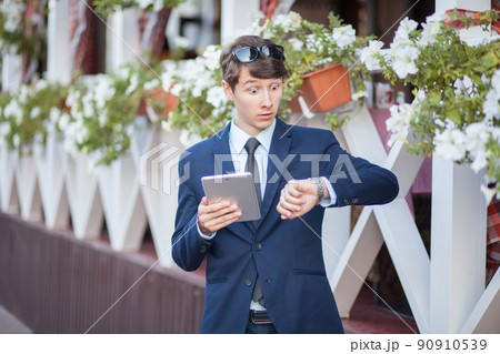 young man in business suit holding tablet on summertime day. young man in business suit holding tablet on summertime day. 90910539