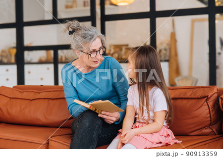Nice elderly woman grandmother reading story to granddaughter. Nice elderly woman grandmother reading story to granddaughter. 90913359