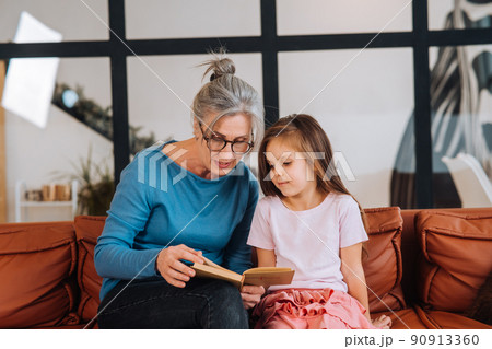Nice elderly woman grandmother reading story to granddaughter. Nice elderly woman grandmother reading story to granddaughter. 90913360
