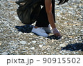 woman's hand collects garbage on the beach with gloves 90915502