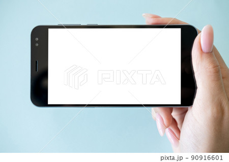 Mobile entertainment. Digital mockup. Online connection. Female hand holding smartphone with white blank screen isolated blue. 90916601