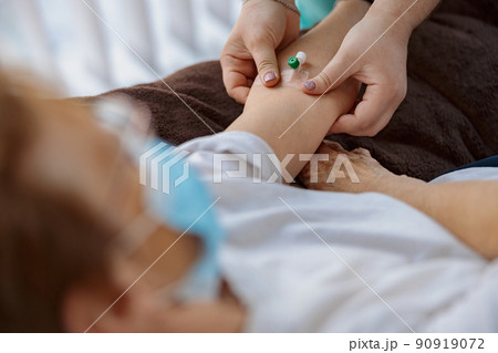 Nurse putting a drip in the arm of her patient in modern medical clinic Nurse putting a drip in the arm of her patient in modern medical clinic 90919072
