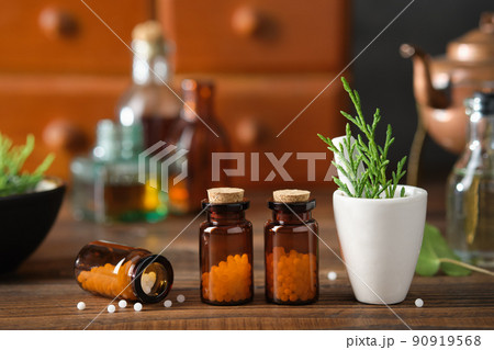 Bottles of homeopathic granules, cabinet with homeopathic remedies and tincture bottles on background. Homeopathy medicine concept. 90919568