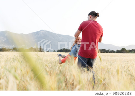 Dad spins his daughter on field , having fun at sunset. Father plays with child. Happy family and childhood concept. Dad spins his daughter on field , having fun at sunset. Father plays with child. Happy family and childhood concept. 90920238