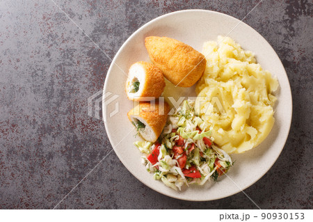 Chicken Kiev cutlets served with salad and mashed potatoes closeup in the plate. Horizontal top view Chicken Kiev cutlets served with salad and mashed potatoes closeup in the plate. Horizontal top view 90930153