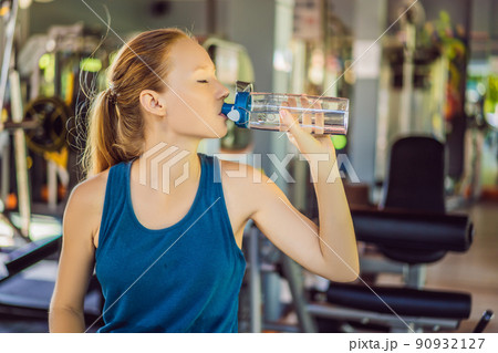 Young athletic woman drinking water in gym 90932127