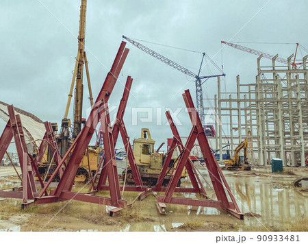 construction site of an industrial complex. red structures stacked together for fall protection. long metal sticks for building foundations and strengthening buildings construction site of an industrial complex. red structures stacked together for fall protection. long metal sticks for building foundations and strengthening buildings 90933481