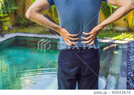 Men's back hurts against the backdrop of the pool. Pool helps with back pain 90933678