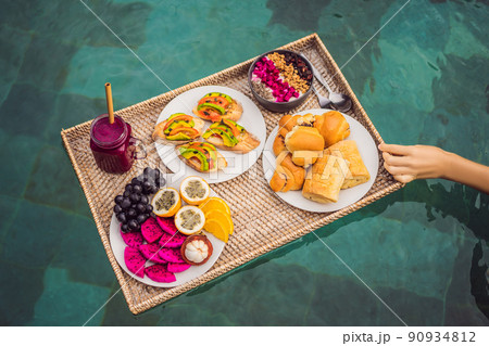 Breakfast tray in swimming pool, floating breakfast in luxury hotel smoothies and fruit plate, smoothie bowl by the hotel pool. Exotic summer diet. Tropical beach lifestyle. Bali Trend 90934812