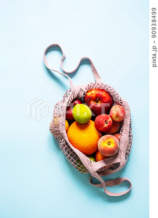 String mesh bag for grocery with various fruits. Reusable shopping tote bag, zero waste concept. 90938499