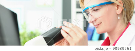 Joyful woman looks into a magnifying device, close-up Joyful woman looks into a magnifying device, close-up 90939561