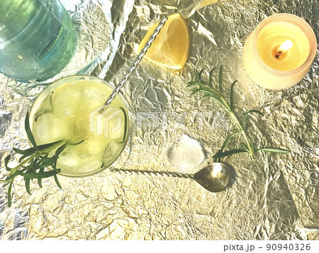 Cold lemon drink into which one can add some alcohol with ice cubes and mint on steel background with candles Cold lemon drink into which one can add some alcohol with ice cubes and mint on steel background with candles 90940326