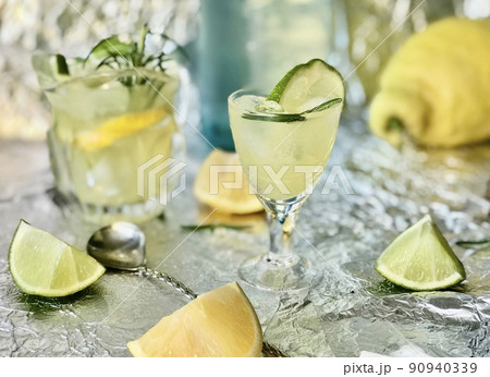 Cold lemon drink into which one can add some alcohol with ice cubes and mint on steel background with candles Cold lemon drink into which one can add some alcohol with ice cubes and mint on steel background with candles 90940339