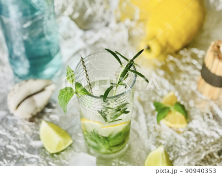 Cold lemon drink into which one can add some alcohol with ice cubes and mint on steel background with candles Cold lemon drink into which one can add some alcohol with ice cubes and mint on steel background with candles 90940353