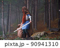 Red-haired girl in armor and raincoat in forest. Historical concept 90941310