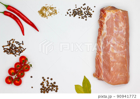 Meat and spices. Isolated. Large piece of meat, red hot chili pepper, cherry tomatoes, cumin, black peppercorns, cloves, bay leaf, dried spices on white background. Copy space for text, ads. Close-up 90941772