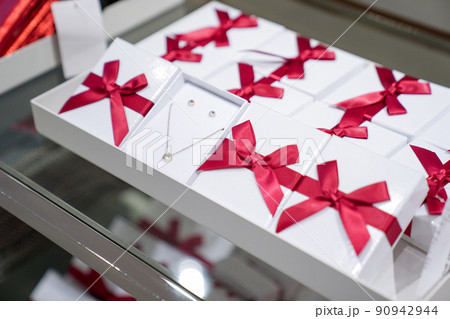 Pendant and earring in the paper box with red bow are display for sales in the fashion jewellry store. Pendant and earring in the paper box with red bow are display for sales in the fashion jewellry store. 90942944