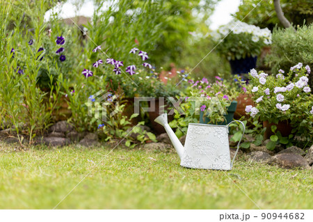 庭に置いてある白いブリキのじょうろ 90944682