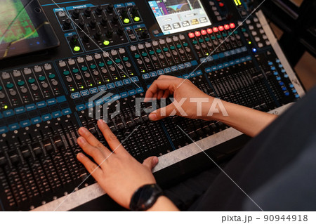 Dj controles sound controller and plays mixed edm music in the concert nightclub at a party. 90944918