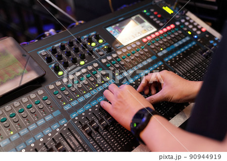 Dj controles sound controller and plays mixed edm music in the concert nightclub at a party. 90944919