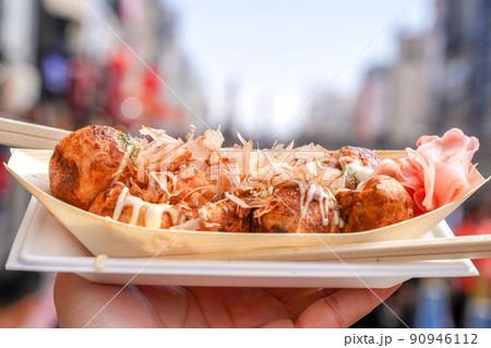Takoyaki, Local Japanese octopus meat ball in the hand with blur cityscape, ready to eat. Takoyaki, Local Japanese octopus meat ball in the hand with blur cityscape, ready to eat. 90946112