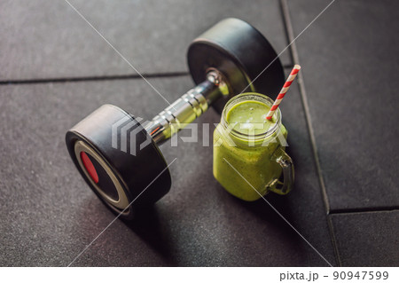 Green smoothies and dumbbells in the gym 90947599