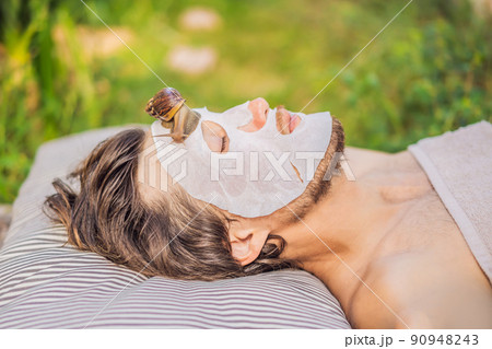 Young man makes a face mask with snail mucus. Snail crawling on a face mask. SPA for man, SPA for all 90948243