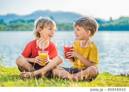 Two boys drink healthy smoothies against the backdrop of palm trees. Mango and watermelon smoothies. Healthy nutrition and vitamins for children 90948930