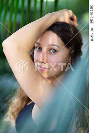 Young beautiful natural cheerful woman with healthy face and skin in exotic greenery. Closeup fresh face of attractive girl. Summer model. Natural beauty concept Young beautiful natural cheerful woman with healthy face and skin in exotic greenery. Closeup fresh face of attractive girl. Summer model. Natural beauty concept 90949160