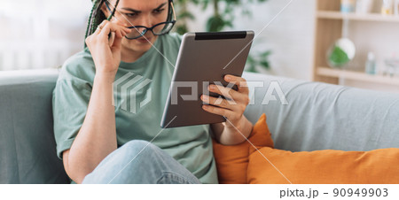 Girl with poor eyesight reads book on tablet Girl with poor eyesight reads book on tablet 90949903