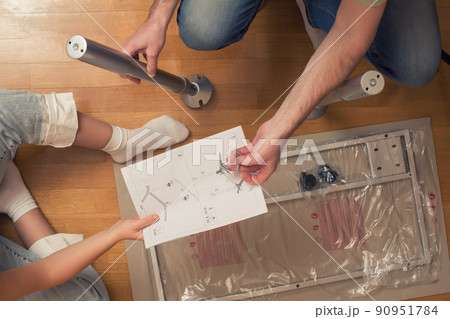 Man and woman assembling furniture on wooden parquet using instruction for for self assembly Man and woman assembling furniture on wooden parquet using instruction for for self assembly 90951784