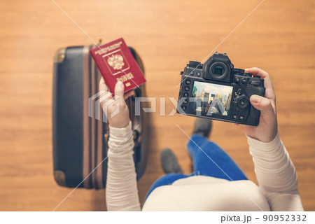 Top view on a girl looking a photos from New York city on her camera standing with suitcase in the airport. The girl returns home after trip to America. 90952332