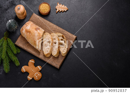 French baguette bread sliced on a wooden cutting board against a dark concrete background French baguette bread sliced on a wooden cutting board against a dark concrete background 90952837