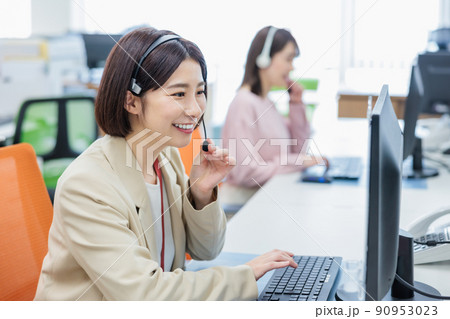 電話を受けるコールセンターのオペレーター 90953023