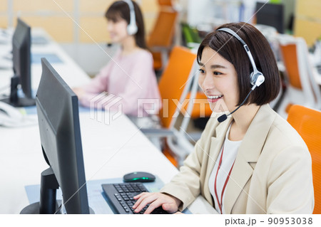 電話を受けるコールセンターのオペレーター 90953038