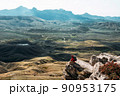 A male tourist is resting after a hard climb up the mountain, panorama. A traveler among the Rocky Mountains. A man is a traveler with a backpack among the rocks. Backpacking in the mountains 90953175