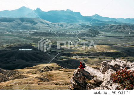 A male tourist is resting after a hard climb up the mountain, panorama. A traveler among the Rocky Mountains. A man is a traveler with a backpack among the rocks. Backpacking in the mountains A male tourist is resting after a hard climb up the mountain, panorama. A traveler among the Rocky Mountains. A man is a traveler with a backpack among the rocks. Backpacking in the mountains 90953175
