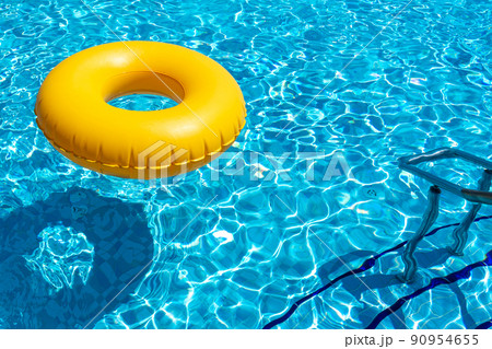 Yellow ring floating in refreshing blue swimming pool Yellow ring floating in refreshing blue swimming pool 90954655