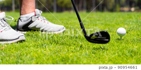 Man standing with golf iron club ready to hit a ball on green grass on golf course 90954661