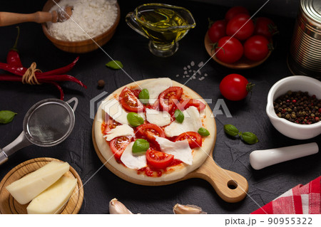 Italian pizza with ingredients on table. Pizza cooking at tabletop background Italian pizza with ingredients on table. Pizza cooking at tabletop background 90955322