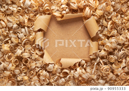 Wood shavings at torn paper background. Wooden shaving on cardboard texture Wood shavings at torn paper background. Wooden shaving on cardboard texture 90955333
