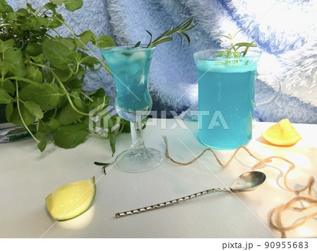 Blue cold drink in a glass with ice cubes on natural sun light. Blue cold drink in a glass with ice cubes on natural sun light. 90955683