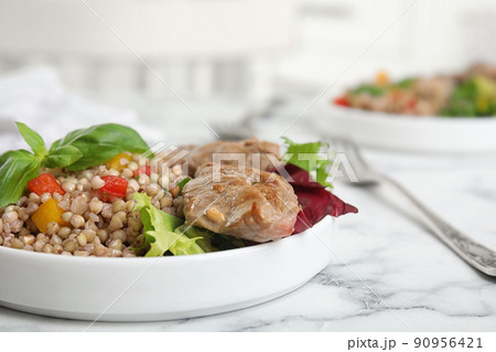 Tasty buckwheat porridge with meat on white marble table, closeup 90956421