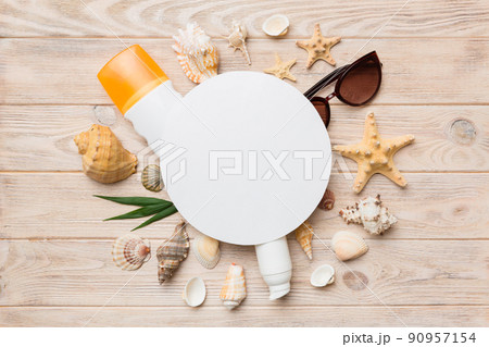 Summer time concept with blank greeting card and blank white paper on colored background. Seashells from ocean shore in the shape of frame separated with space for text top view 90957154