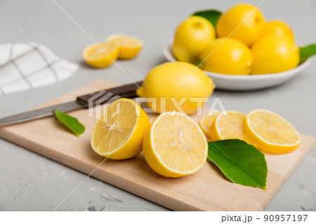 Top view with copy space for fresh and ripe lemons on cutting board. Healthy food background. Elegant background of lemon and lemon slices with squeezer colored background Top view with copy space for fresh and ripe lemons on cutting board. Healthy food background. Elegant background of lemon and lemon slices with squeezer colored background 90957197