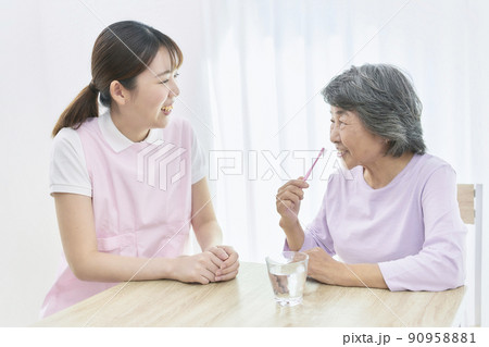 シニアの歯磨き指導をする若い歯科衛生士 90958881